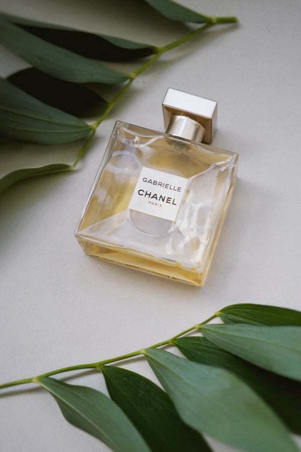 Bottle of perfume, Gabrielle by Chanel, and laurel leaves.