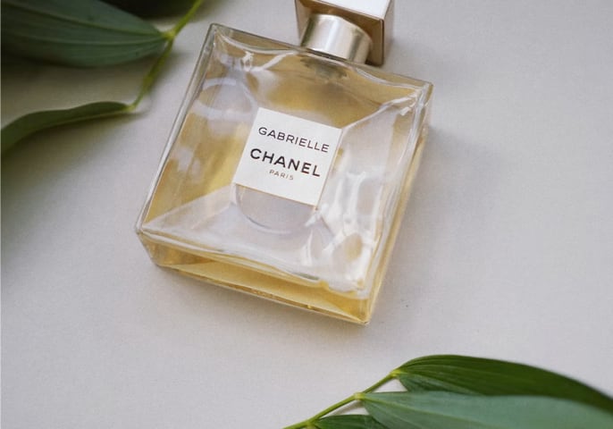 Bottle of perfume, Gabrielle by Chanel, and laurel leaves.